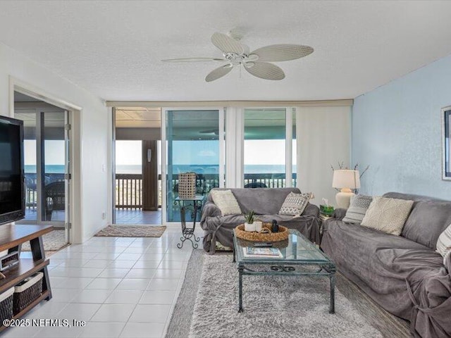 tiled living room with ceiling fan, a healthy amount of sunlight, and a textured ceiling