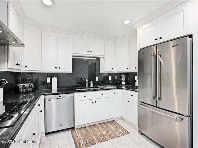 kitchen with sink, wall chimney exhaust hood, decorative backsplash, white cabinetry, and stainless steel appliances