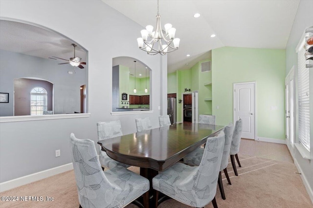 carpeted dining room with ceiling fan with notable chandelier and lofted ceiling