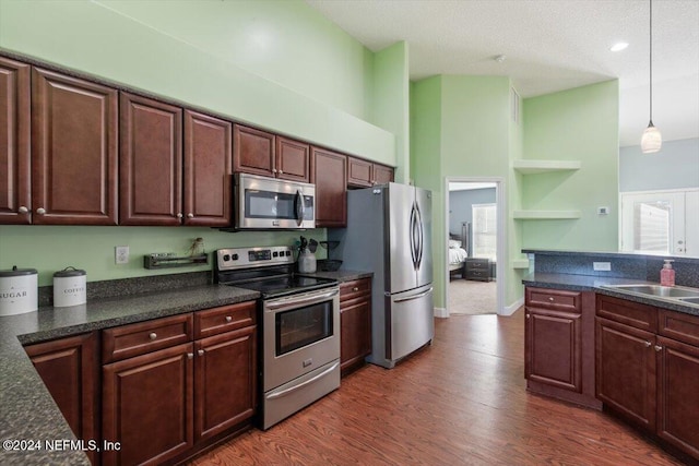 kitchen featuring sink, dark hardwood / wood-style floors, pendant lighting, dark brown cabinets, and appliances with stainless steel finishes