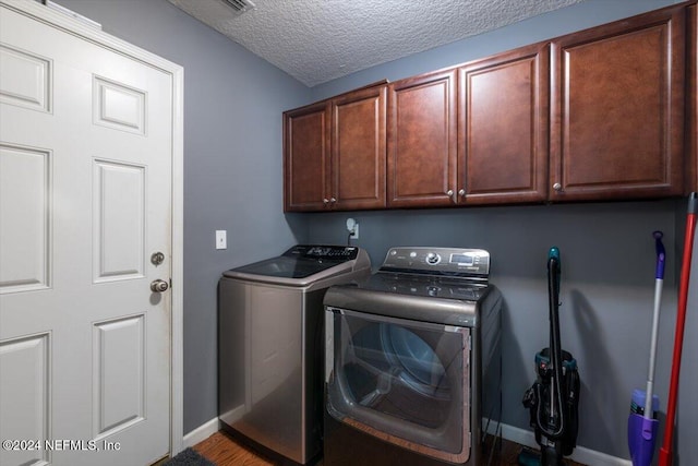 laundry area with cabinets, a textured ceiling, and separate washer and dryer