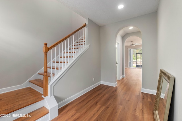 stairs with ceiling fan and hardwood / wood-style flooring