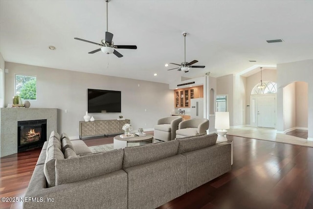 living room with lofted ceiling, ceiling fan, and dark wood-type flooring