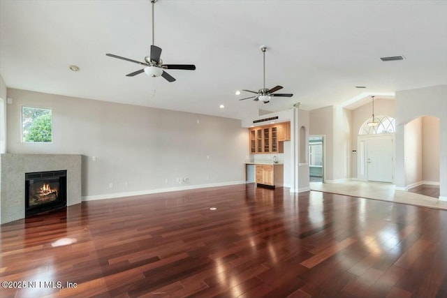 unfurnished living room with dark hardwood / wood-style flooring, ceiling fan, a fireplace, and vaulted ceiling