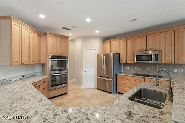 kitchen with backsplash, light stone countertops, sink, and appliances with stainless steel finishes