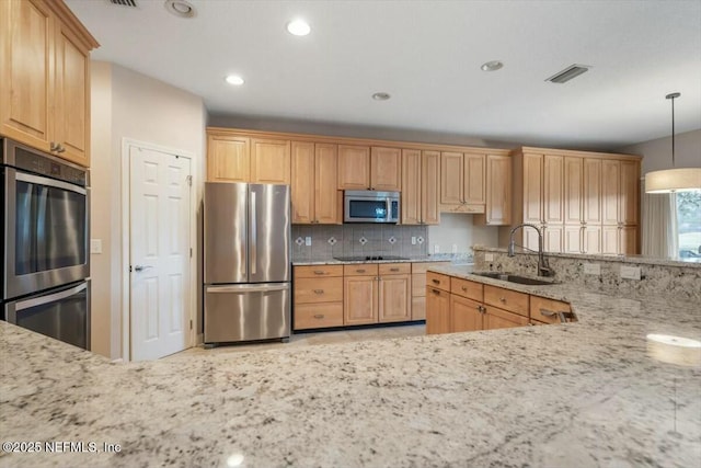 kitchen featuring decorative backsplash, appliances with stainless steel finishes, light stone counters, sink, and decorative light fixtures