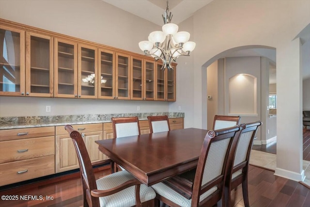 dining room with dark hardwood / wood-style floors, lofted ceiling, and an inviting chandelier