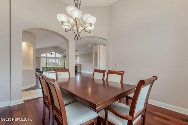 dining space with ceiling fan with notable chandelier, lofted ceiling, and dark wood-type flooring