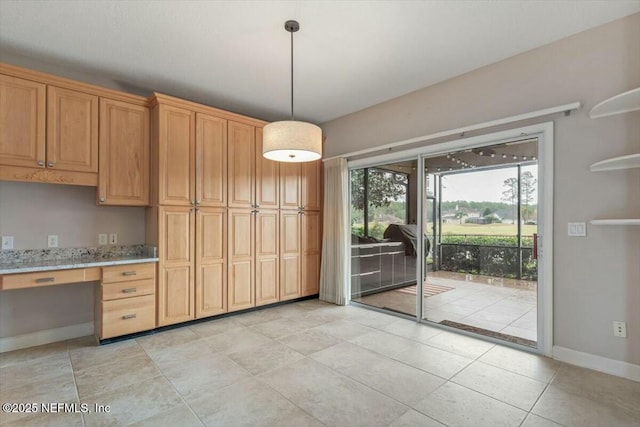 kitchen with built in desk, decorative light fixtures, and light stone counters