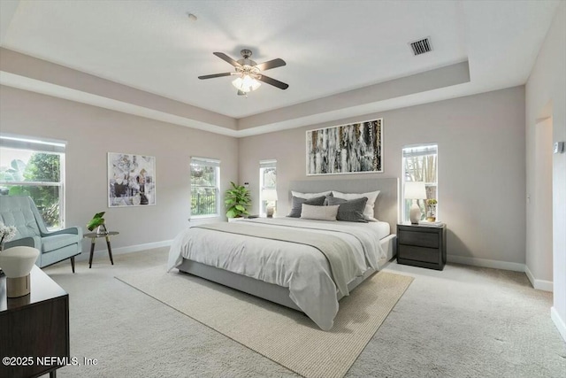 carpeted bedroom featuring a tray ceiling and ceiling fan