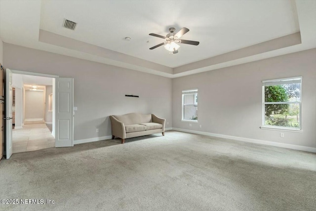 unfurnished room featuring ceiling fan, a raised ceiling, and light carpet