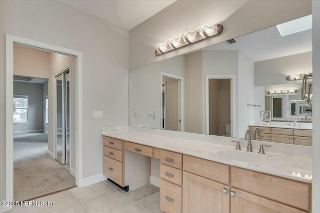 bathroom with tile patterned floors, vanity, a skylight, and toilet