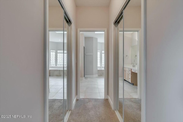 hallway with light carpet and sink