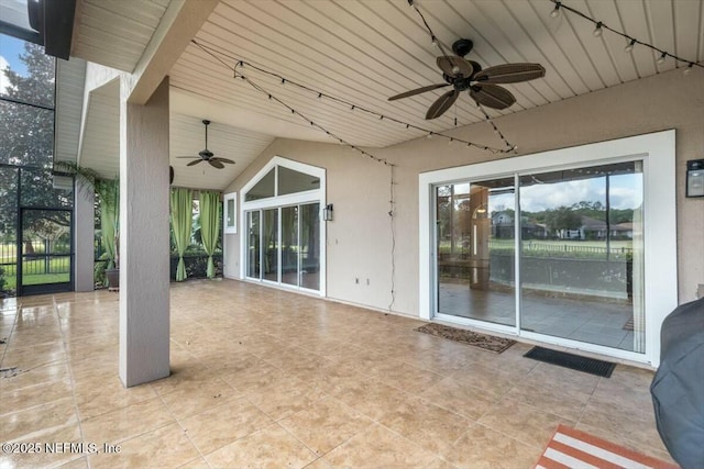 view of patio / terrace featuring ceiling fan and glass enclosure