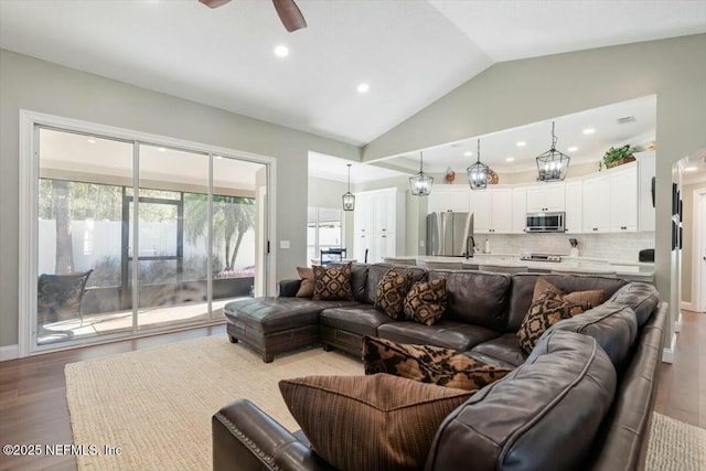 living room featuring ceiling fan, light hardwood / wood-style floors, and vaulted ceiling