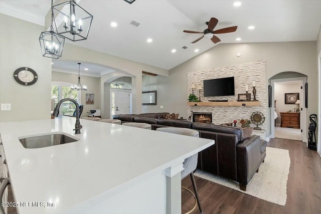 kitchen featuring ceiling fan, sink, pendant lighting, lofted ceiling, and a fireplace