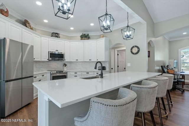 kitchen featuring a breakfast bar, a large island with sink, sink, appliances with stainless steel finishes, and white cabinetry