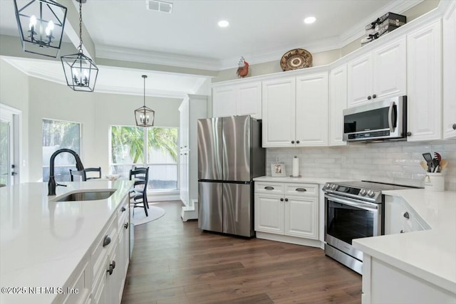 kitchen featuring decorative backsplash, appliances with stainless steel finishes, sink, white cabinets, and hanging light fixtures