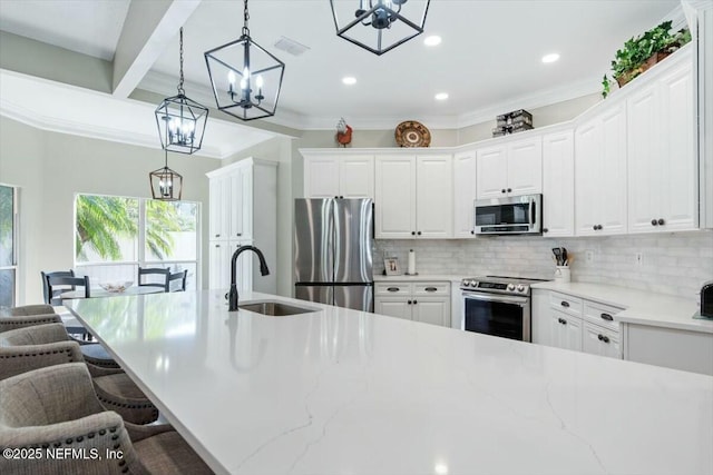 kitchen featuring sink, pendant lighting, a kitchen bar, white cabinets, and appliances with stainless steel finishes