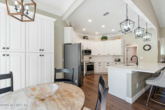 kitchen featuring pendant lighting, white cabinetry, sink, and appliances with stainless steel finishes