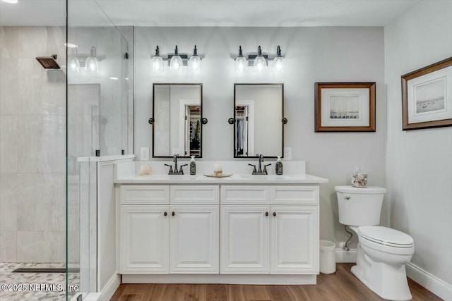 bathroom with tiled shower, vanity, hardwood / wood-style flooring, and toilet