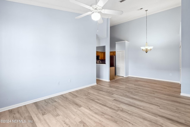 empty room featuring ornamental molding, ceiling fan with notable chandelier, and light wood-type flooring