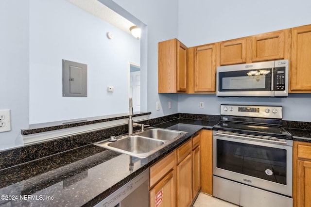 kitchen with dark stone countertops, sink, stainless steel appliances, and electric panel