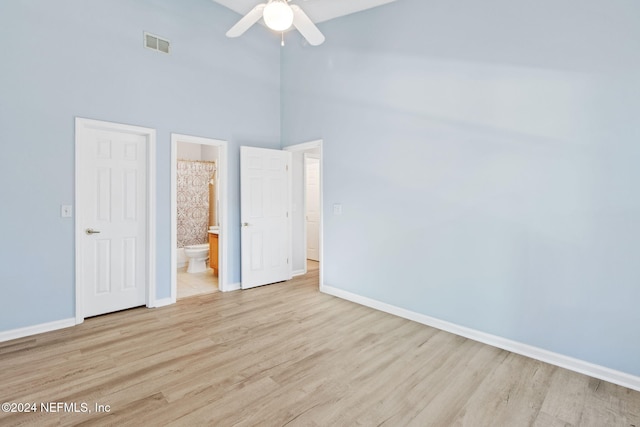 unfurnished bedroom with ensuite bath, ceiling fan, light hardwood / wood-style floors, and a high ceiling