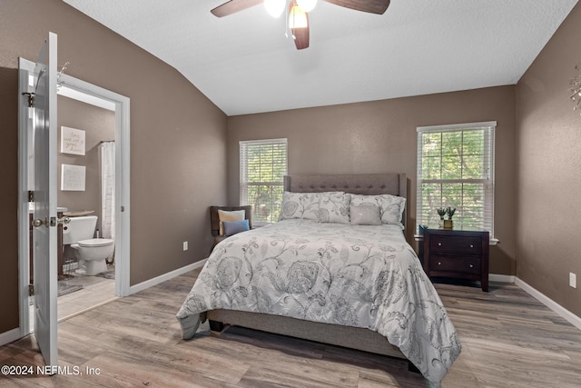 bedroom featuring connected bathroom, ceiling fan, light hardwood / wood-style floors, and vaulted ceiling