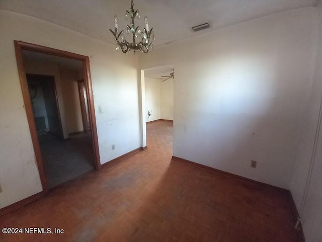 spare room with ceiling fan with notable chandelier and dark parquet floors