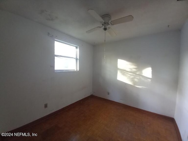 spare room with dark parquet flooring and ceiling fan