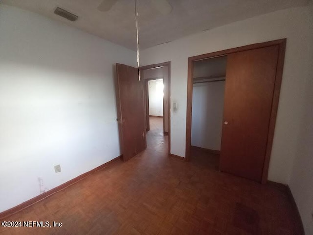 unfurnished bedroom with parquet floors, a closet, and ceiling fan