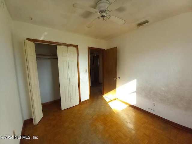 unfurnished bedroom with ceiling fan, parquet flooring, and a closet