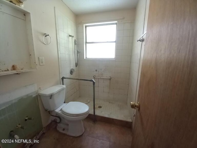 bathroom featuring tile patterned floors, toilet, and tiled shower