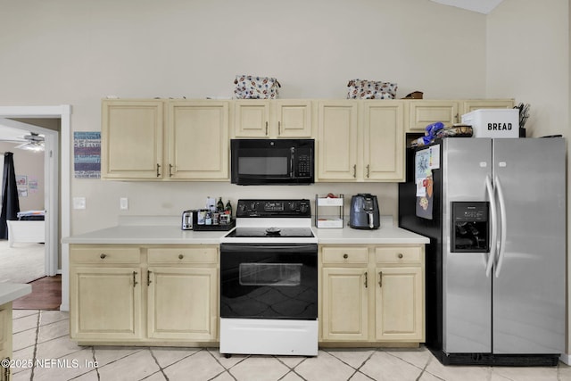 kitchen featuring cream cabinetry, stainless steel fridge, light tile patterned floors, and white range with electric cooktop