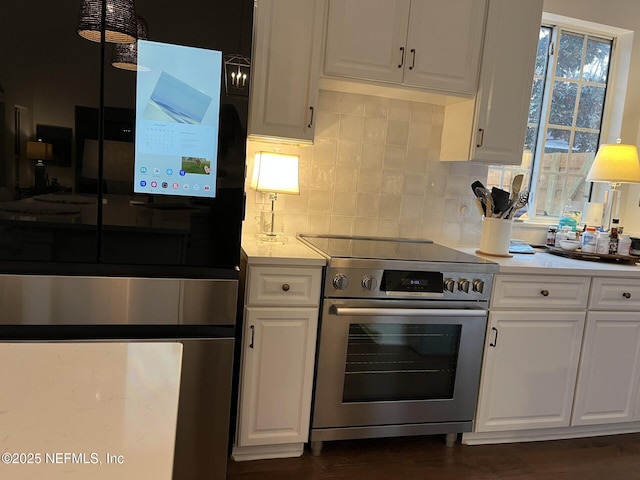 kitchen with decorative backsplash, white cabinets, and electric stove