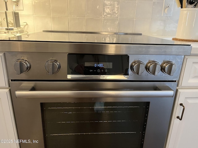 details featuring white cabinetry, oven, and backsplash