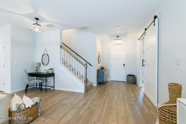 entryway with a barn door and light hardwood / wood-style flooring