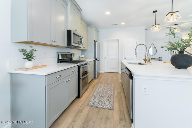 kitchen with pendant lighting, stainless steel appliances, light hardwood / wood-style flooring, and sink