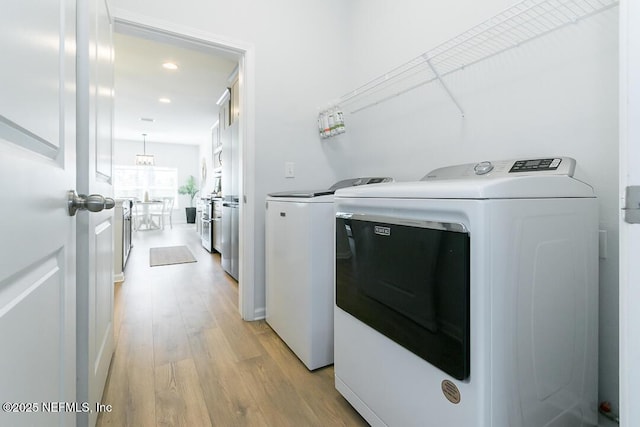 clothes washing area with washer and dryer and light wood-type flooring