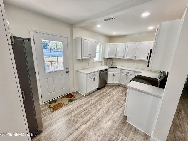 kitchen with sink, stainless steel appliances, light hardwood / wood-style flooring, and white cabinetry