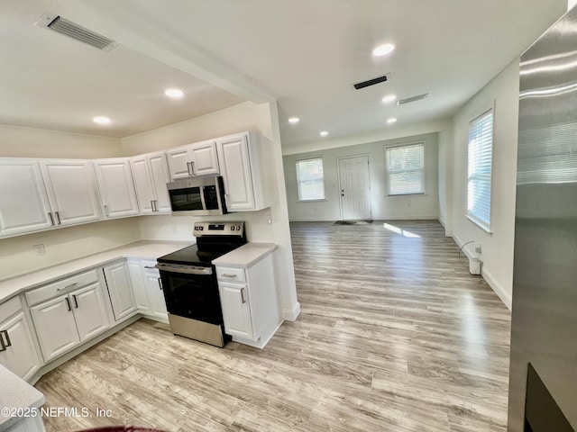 kitchen featuring stainless steel appliances, white cabinetry, a healthy amount of sunlight, and light hardwood / wood-style floors