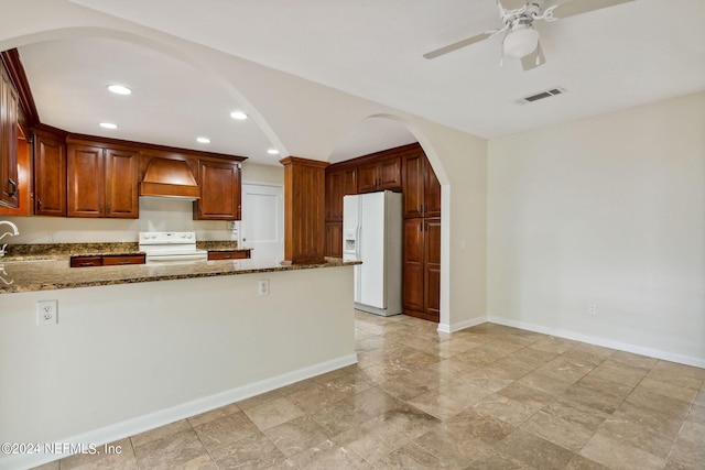 kitchen with ceiling fan, sink, dark stone counters, white appliances, and custom range hood