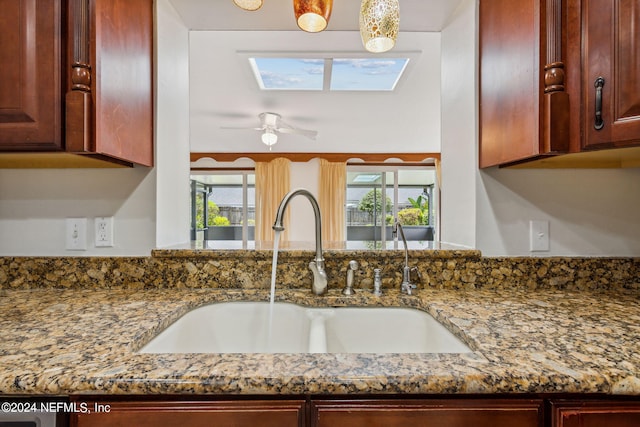 room details with ceiling fan, dark stone countertops, and sink