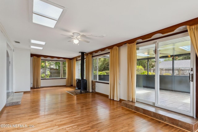 interior space with light hardwood / wood-style floors, a wood stove, and ceiling fan