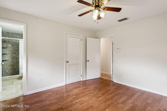 unfurnished bedroom with ensuite bathroom, ceiling fan, and hardwood / wood-style flooring