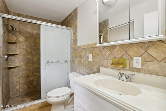 bathroom with tile patterned floors, vanity, toilet, and tiled shower