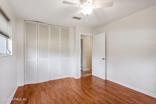 unfurnished bedroom featuring ceiling fan, a closet, and wood-type flooring