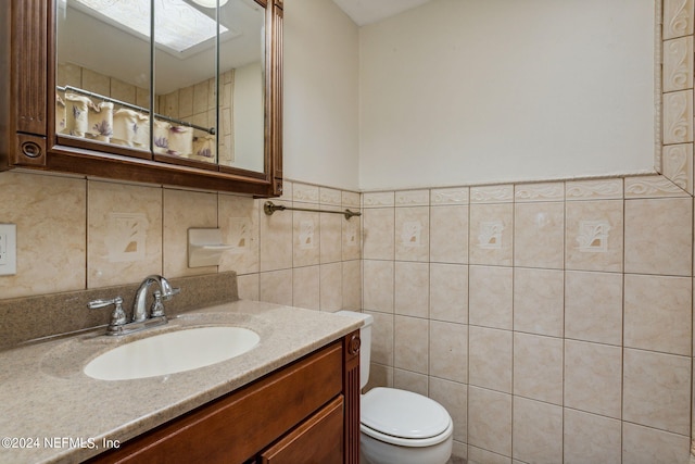 bathroom with a shower with shower curtain, vanity, toilet, and tile walls