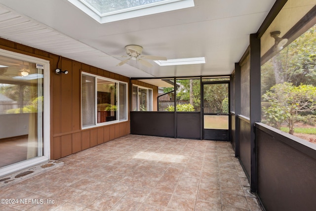 unfurnished sunroom featuring ceiling fan, a wealth of natural light, and a skylight